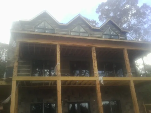 Dormers and porch framing on a large log home under construction — Roof Coating work by our crew in Dublin